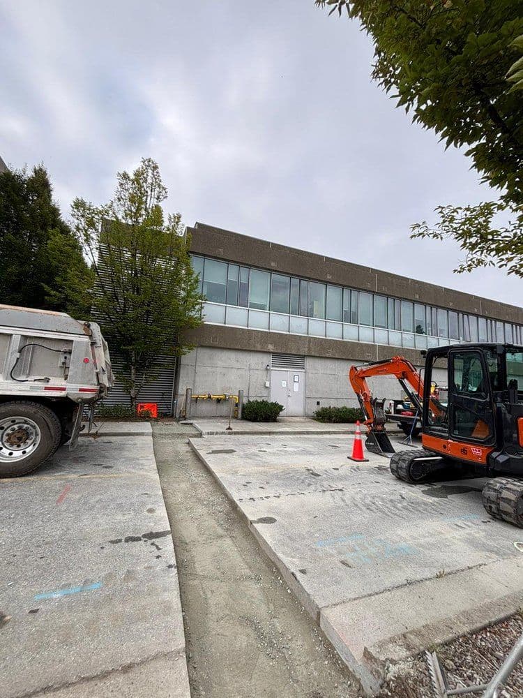Construction site with heavy machinery and a modern building under renovation.